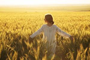 gelukkige vrouw in jurk in het midden van een veld met rijpe rogge foto