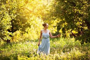 jonge vrouw in blauwe jurk loopt in de tuin
