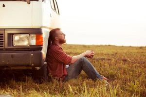 bestuurder rust in een veld in de buurt van zijn auto foto