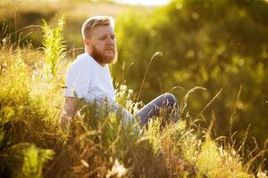 man met een rode baard zit op het gras foto