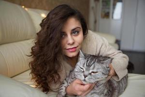 jonge vrouw die een grijze kat aait foto