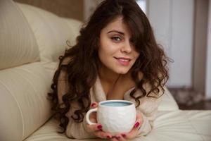 mooi meisje ligt met een kopje koffie