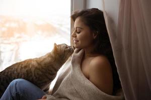 meisje en een grote kat bij het raam foto