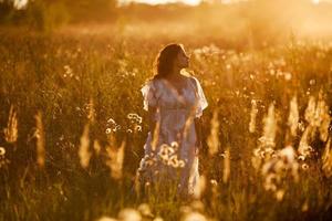 meisje staat in het veld bij zonsondergang
