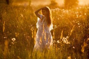 vrouw die in het veld staat bij zonsondergang foto