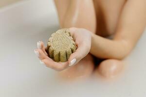 vrouw handen Holding een shampoo bar, biologisch zeep in een bad. schoonheid blog, salon concept, minimalisme. behandeling, zorg en spa procedures. foto