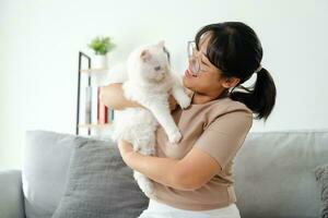 gelukkig vrouw spelen met kat in knus leven kamer Bij huis. foto