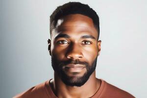 een jong Afro-Amerikaans Mens in een bruin t-shirt poses tegen een grijs achtergrond. Mens op zoek Bij camera. ai generatief foto