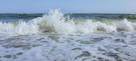 zeegezicht. azuurblauwe kleur van water, golven schuimend op de kust. foto