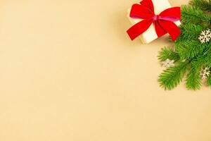 Kerstmis vlak leggen met geschenk boxe en rood lint decoratie, Kerstmis boom takken Aan ambacht papier achtergrond. feestelijk gestileerd mockup samenstelling. top visie. kopiëren ruimte. foto