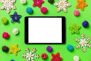 top visie van digitaal tablet. nieuw jaar decoraties Aan groen achtergrond. feestelijk sterren en ballen. vrolijk Kerstmis concept foto