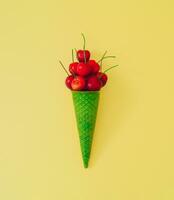 rood kers fruit in groen ijshoorntje Aan pastel geel achtergrond. minimaal zomer fruit concept. creatief zomer ijs room idee. vlak leggen kers regeling. top van visie. foto