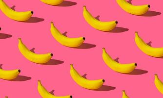 modieus fruit patroon gemaakt van vers banaan Aan licht pastel roze achtergrond. minimaal banaan patroon indeling. natuur zomer achtergrond concept. foto