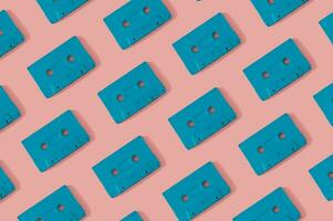 patroon gemaakt met retro blauw audio cassette banden Aan modern roze achtergrond. creatief concept van retro technologie. 80's stijlvol. retro wijnoogst audio cassette plakband patroon idee. vlak leggen. foto