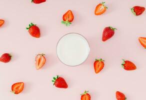 creatief patroon samenstelling gemaakt van melk drinken met aardbei smaak in glas kop en rood aardbeien Aan pastel roze achtergrond. minimaal smoothie of milkshake concept. gezond voedsel voor ontbijt. foto