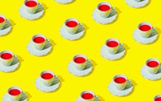 creatief modieus patroon gemaakt van wit kop van rood fruit en kruiden thee Aan geel achtergrond. minimaal natuurlijk heet drinken concept. luxe stoutmoedig kleuren patroon achtergrond idee. fruit thee stijlvol. foto