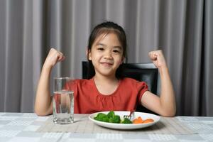 kind shows sterkte van eet groenten en voedzaam voedsel. foto