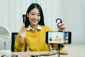 jonge Aziatische beautyblogger presenteert cosmetische producten en tutorials over het aanbrengen en opnemen van make-uptutorials op sociale-medianetwerken. foto