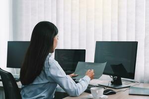 Aziatische vrouw softwareontwikkelaars zitten voor computers en kijken naar computercodes op het scherm. foto