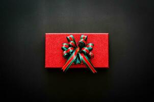 rood geschenk doos met lint Aan zwart achtergrond voor boksen dag en zwart vrijdag boodschappen doen uitverkoop concept. foto
