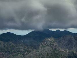 snel verandering in de het weer, een onweersbui voorkant over- hoog bergen, donker beangstigend wolken over- een berg bereik. foto