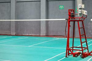 de badminton scheidsrechter stoel is rood met een groen badminton rechtbank achtergrond foto