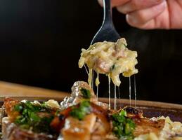 dichtbij omhoog van een vrouw hand- Holding een vork met macaroni en champignons foto