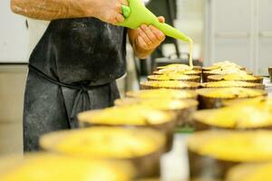 chef produceren panettone, terwijl lieviteren, toevoegen amandel suiker topping naar rauw zoet brood. foto