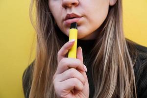 een jong meisje rookt een wegwerp elektronische sigaret