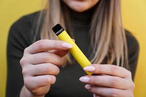 gele wegwerp elektronische sigaret in vrouwelijke hand