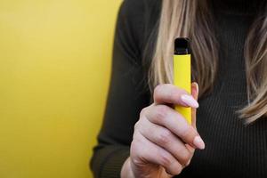 gele wegwerp elektronische sigaret in vrouwelijke hand