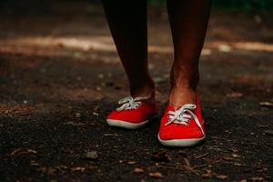 benen in rode sneakers op een herfstpad in het park. zwarte leren poten