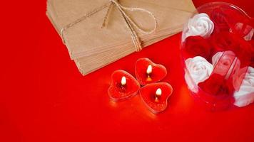 kraftpapier enveloppen met rode kaarsen op een rode achtergrond. foto