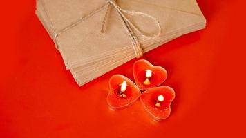 kraftpapier enveloppen met rode kaarsen op een rode achtergrond. foto
