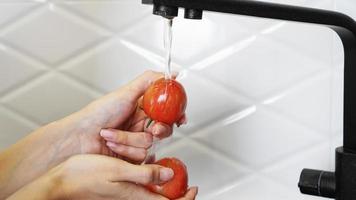 vrouw die tomaten en tomaat in haar handen wast foto