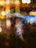 abstract achtergrond herfst regen in de nacht stad, silhouet van een jong vrouw met een paraplu achter een nat venster foto