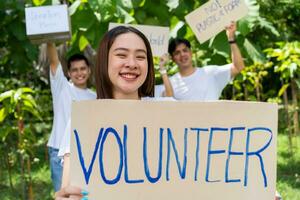 gelukkig jong Aziatisch studenten verschillend vrijwilligers houden een campagne teken voor schoonmaak in de park, de concept van milieu behoud Aan wereld milieu dag, recyclen, liefdadigheid voor duurzaamheid. foto