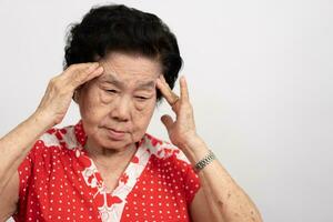 een senior vrouw wie heeft een erge, ernstige hoofdpijn lijdt van een beroerte ,brein ziekte, patiënt Holding hoofd met haar handen, lijden van seniel dementie, geheugen aandoeningen, verward oud ouderen met alzheimer foto