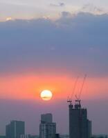 hoog stijgen gebouwen met bouw plaats in zonsondergang foto