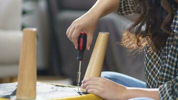 Aziatisch vrouw zelf reparaties meubilair vernieuwing gebruik makend van uitrusting naar diy repareren meubilair zittend Aan de verdieping Bij huis foto