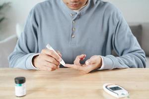 man gebruikt lancet op vinger die bloedsuikerspiegel controleert met glucosemeter. foto