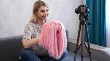 vrouw blogger neemt video op. ze toont roze pruik foto