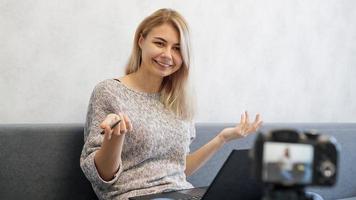 jonge vrouwelijke blogger met laptop en pen die naar de camera kijkt foto