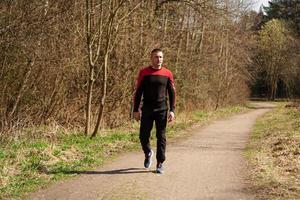 een man in sportkleding op een bospad foto