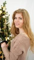 mooie jonge vrouw die een kerstboom versiert foto