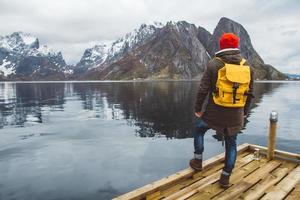 reiziger man staande op de achtergrond van berg en meer houten pier foto
