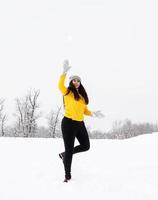 jonge brunette vrouw spelen met sneeuw in park foto