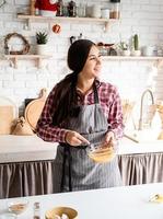 jonge latijnse vrouw die eieren zwaait die in de keuken koken foto