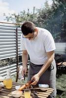 jonge man grillen kebab op spiesjes, man grillen vlees buitenshuis foto