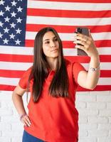 mooie vrouw die een selfie neemt op de achtergrond van de vlag van de VS foto